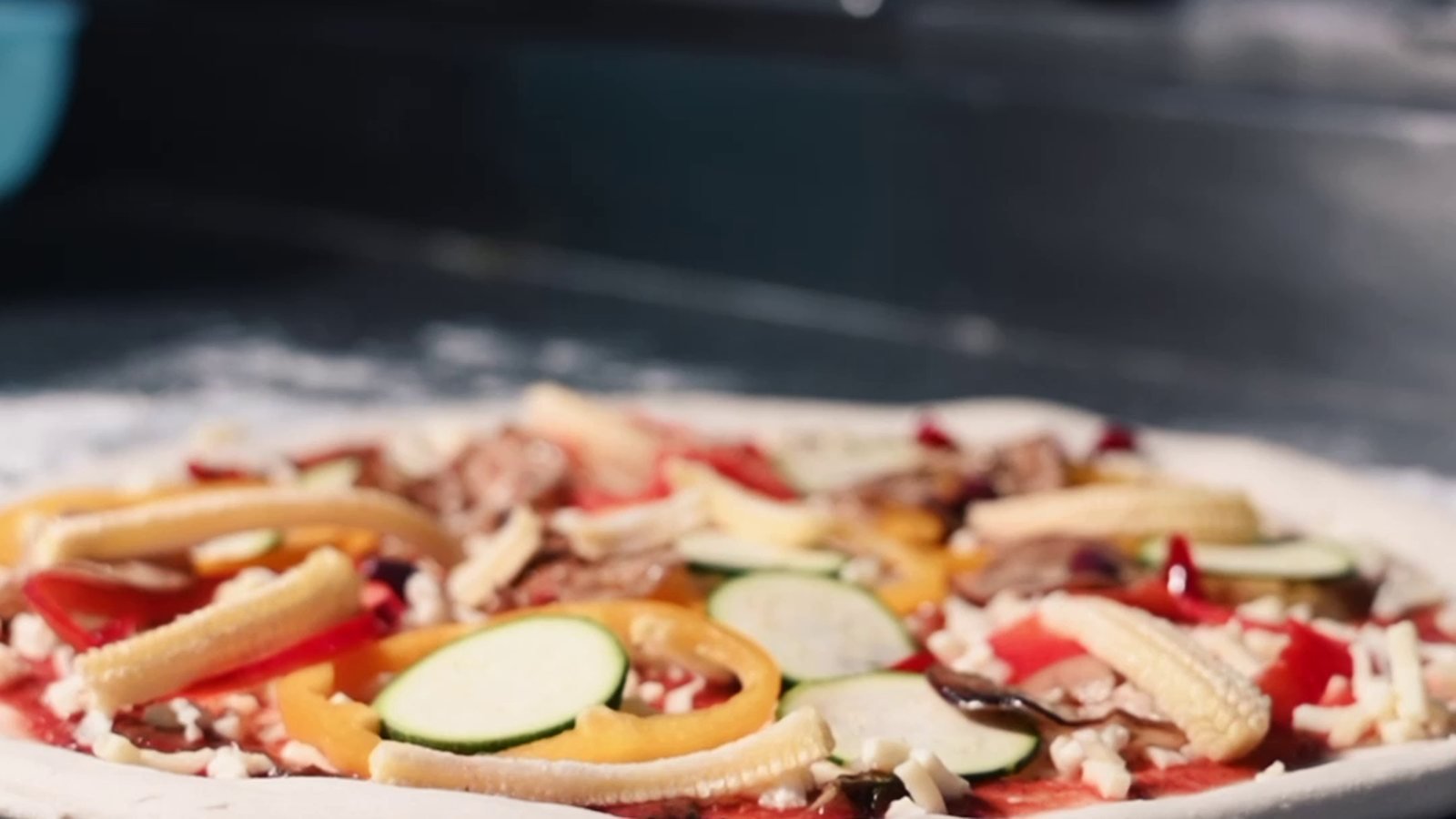 A pizza being dressed before the bake