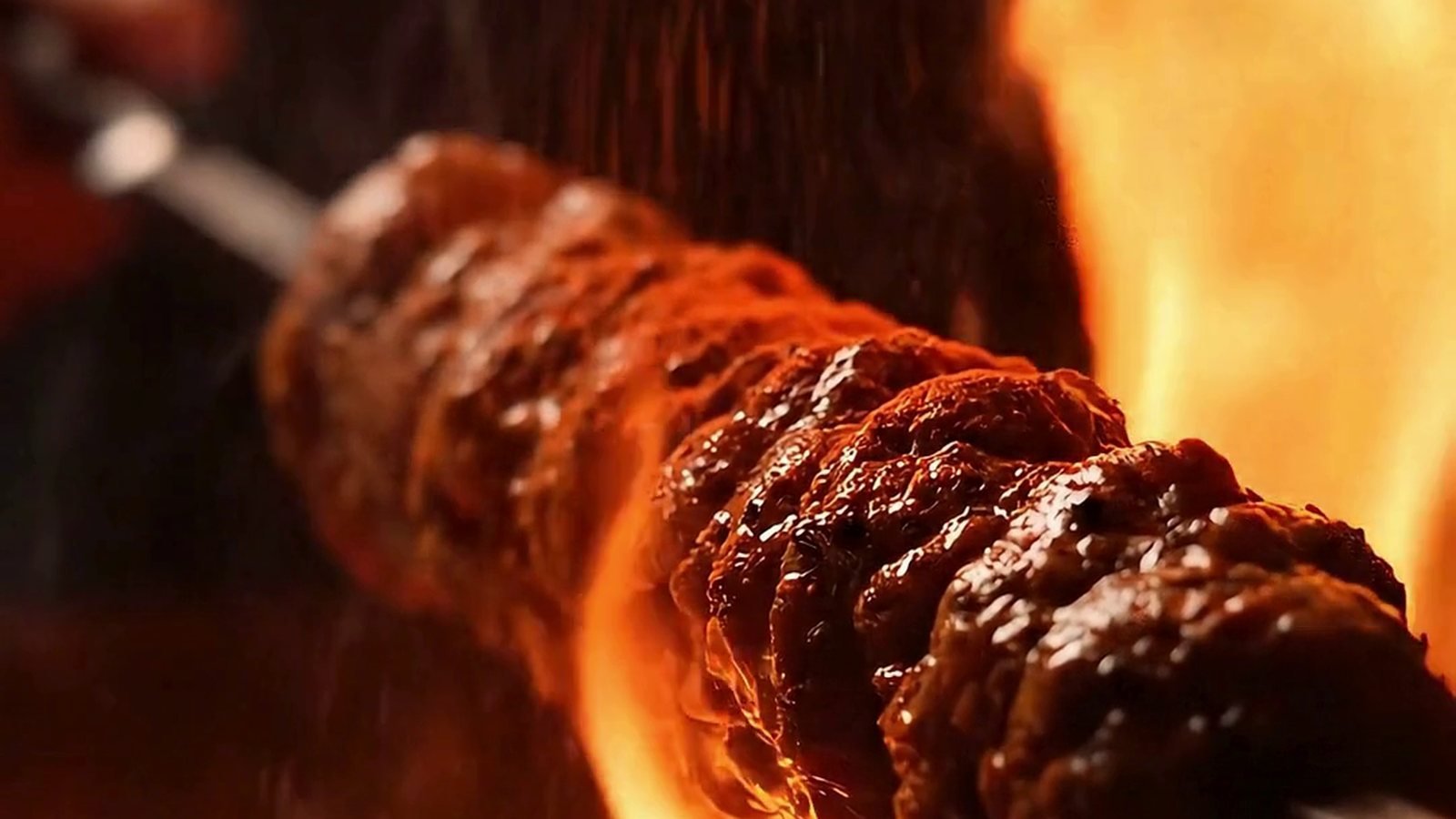 Seekh kebab turning over open flame