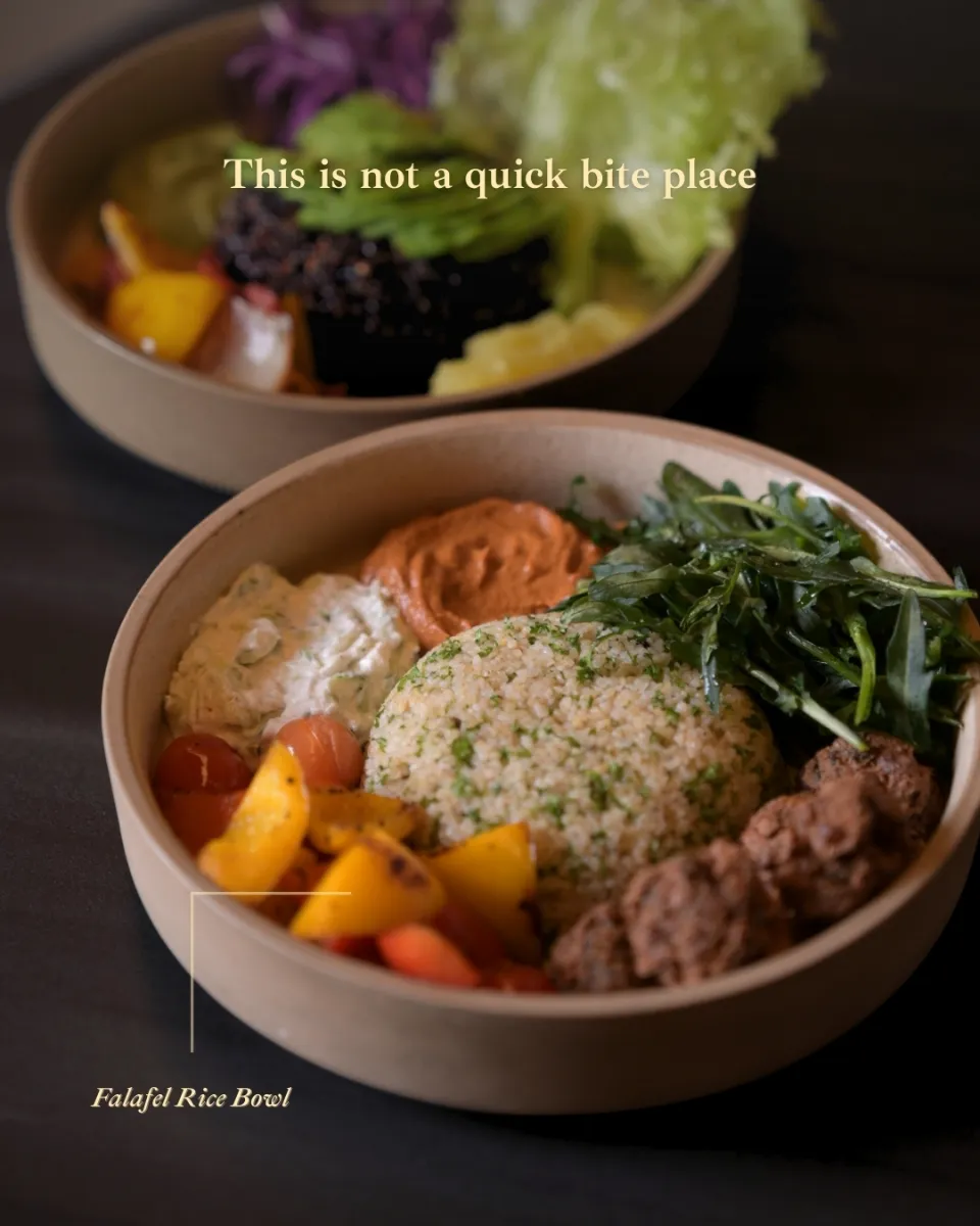 A grain bowl with greens and kofta, shot on a dark table