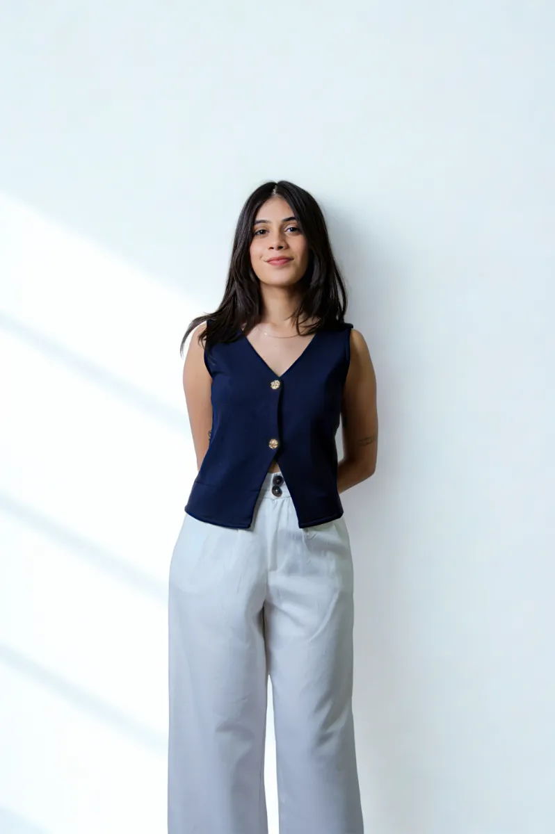 A model in a navy waistcoat and white trousers