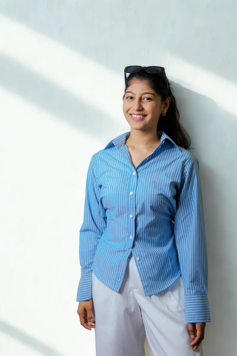A model in a blue striped shirt, hands at her sides