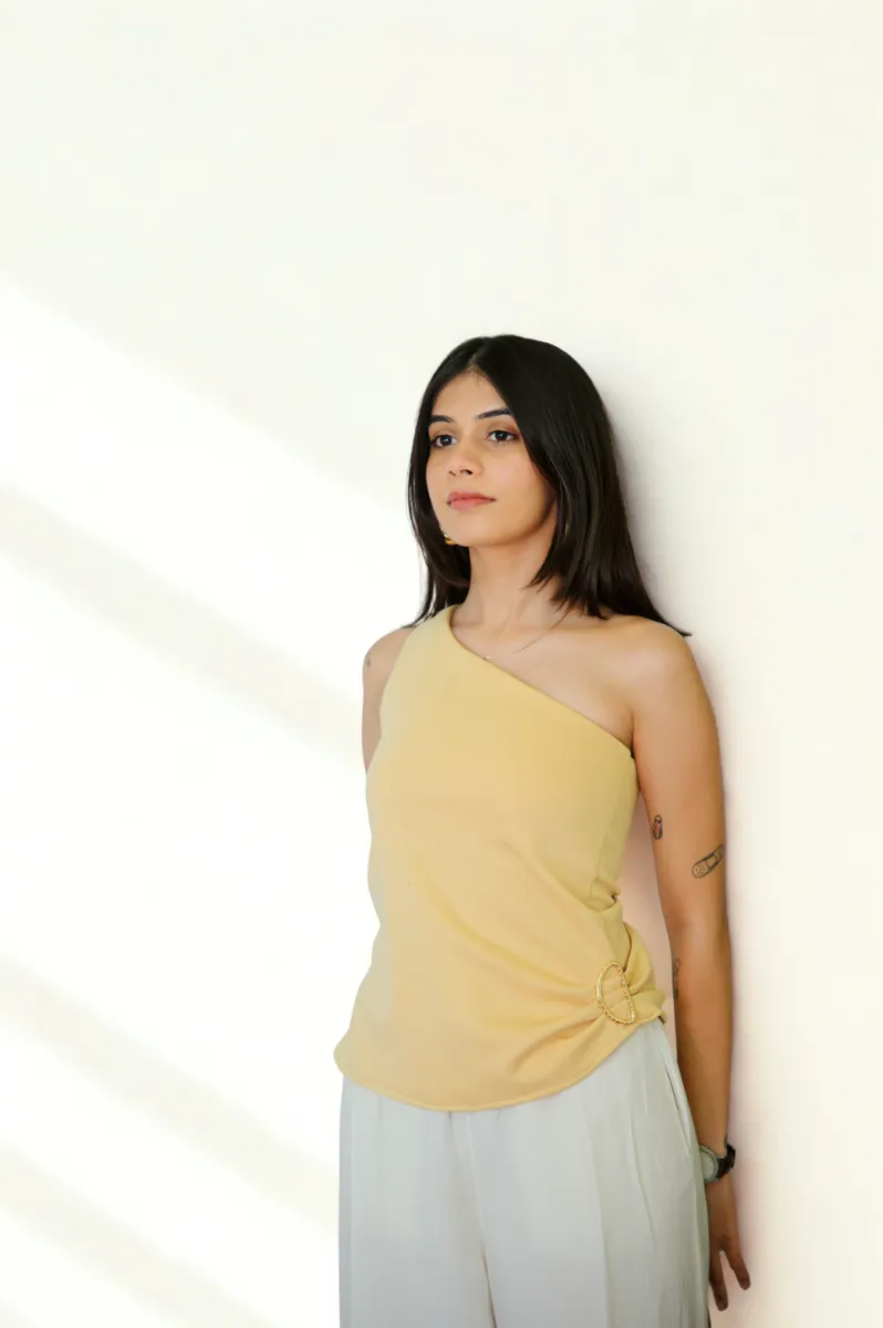 A model in a yellow top against a pale wall